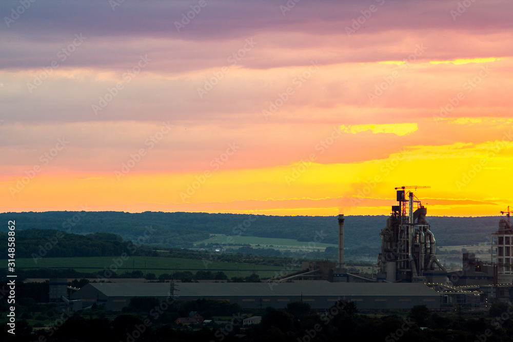 Yellow sunset over industrial landscape with factory chimneys and pipes with smoke polluting the atmosphere.