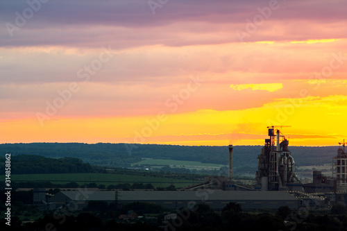 Yellow sunset over industrial landscape with factory chimneys and pipes with smoke polluting the atmosphere.