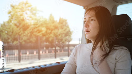 tired woman languishes from hot weather adjusting white sweater neck travelling by car in touristic city