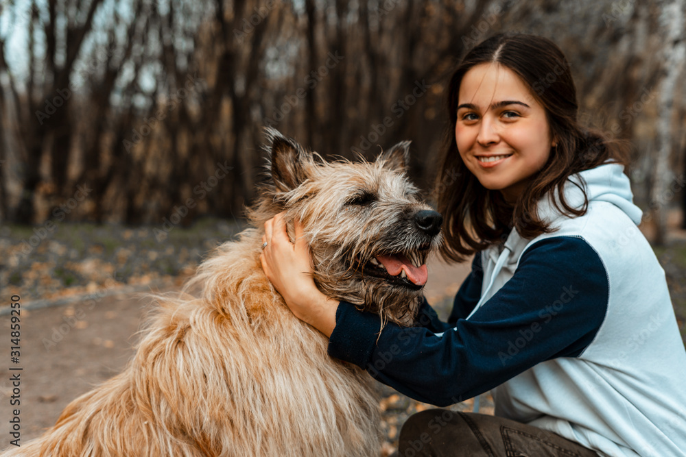 Animal training. A volunteer girl walks with a dog from an animal shelter. Girl with a dog in the autumn park. Walk with the dog. Caring for the animals. Animal training. A volunteer girl walks with a dog from an animal shelter. Girl with a dog in the autumn park. Walk with the dog. Caring for the animals.