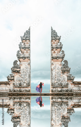 A girl is posing in front of the Gate of Heaven with its reflection in the water. Bali, Indonesia. photo