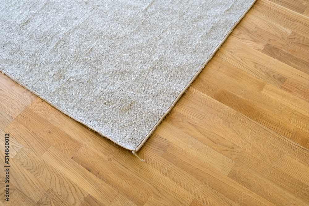 Close up of crumpled carpet laying on parquet wooden floor. - obrazy, fototapety, plakaty 