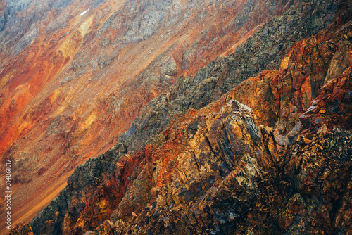 Vivid multicolor nature background of big rocky mountain with pointy rocks. Full frame surface of giant mountain rough wall close-up. Red orange yellow stones. Beautiful natural backdrop of rockies.