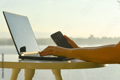 Freelance man using multichannel online network 5G technology internet tablet and laptop working in nature park during relax day time.Sunlight morning, work from anywhere life style concept.