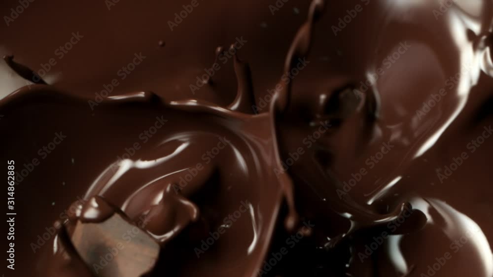 Super Slow Motion Shot of Raw Chocolate Chunks Falling into Melted Chocolate at 1000fps.