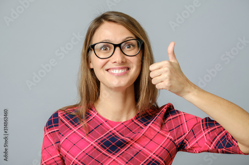 Happy caucasian female wearing red gress making thumb up sign