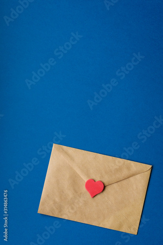 St. Valentine's envelope, letter of craft paper with red heart on classic blue background with copy space. Horizontal. Color 2020.