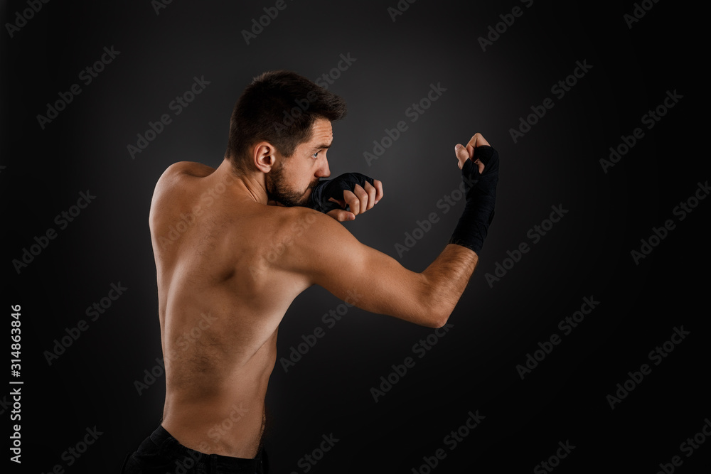 Sportsman boxer throwing a fierce and powerful punch. muscular man on black background.