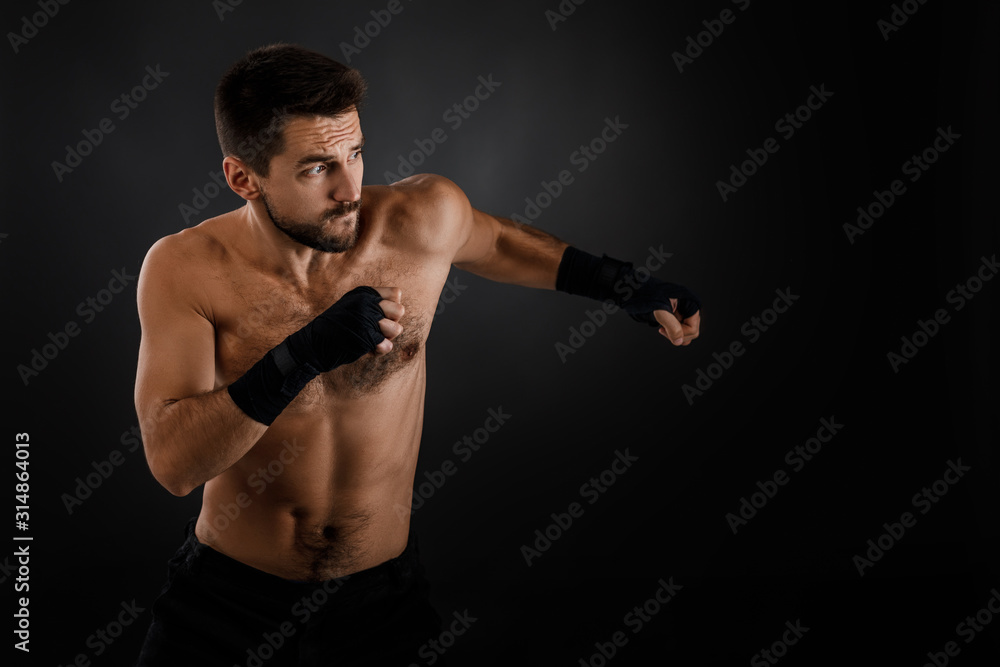 Sportsman boxer throwing a fierce and powerful punch. muscular man on black background. Sportsman boxer throwing a fierce and powerful punch. muscular man on black background.
