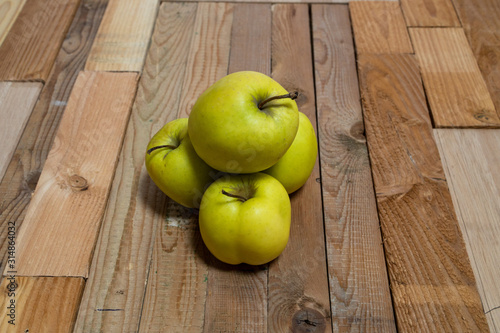 Фотография Four green apples stacked on a wooden board shot from the front in front of a wi