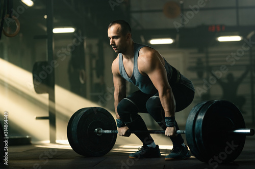 Muscular build man practicing deadlift while exercising in a gym. photo