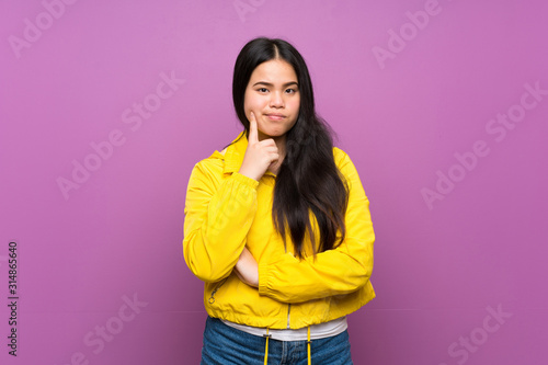 Young teenager Asian girl over isolated purple background Looking front