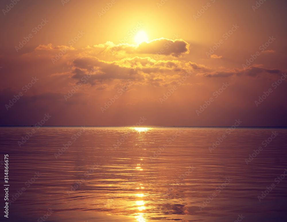 Beautiful golden sunset on the sea, the sun due to clouds reflected in the water