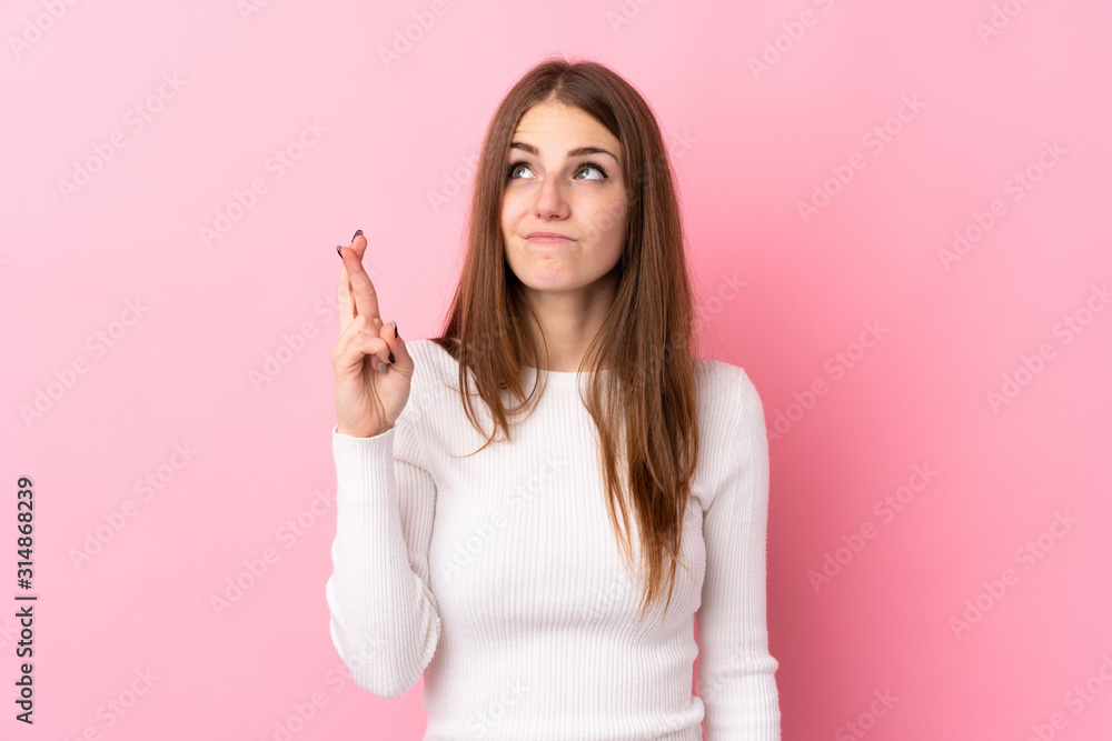 Young woman over isolated pink background with fingers crossing and wishing the best Young woman over isolated pink background with fingers crossing and wishing the best