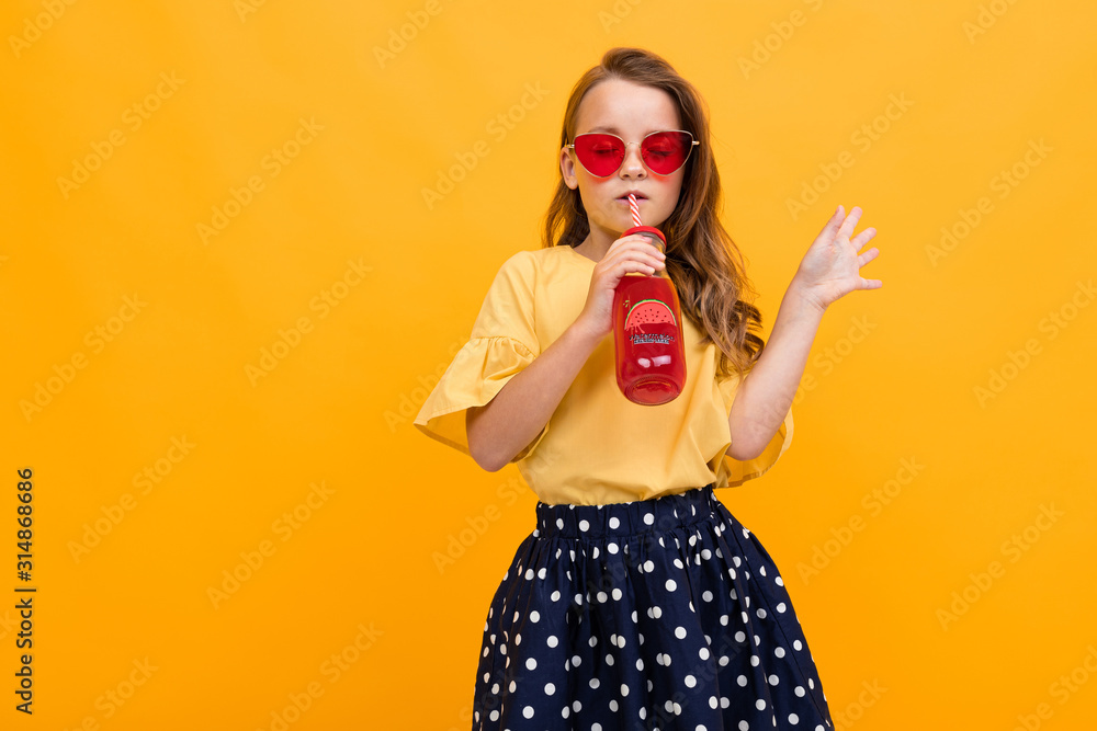 attractive caucasian young girl in a skirt and a t-shirt with a glass of watermelon juice posing on a yellow studio background with copy space attractive caucasian young girl in a skirt and a t-shirt with a glass of watermelon juice posing on a yellow studio background with copy space