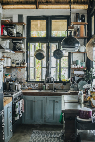 Photography Old crampy rustic kitchen with small window in a tropical house with straw roof