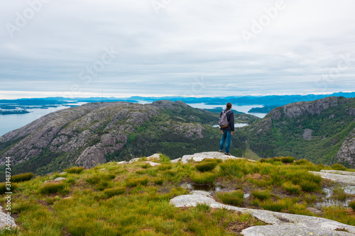 Young man in casual clothes is hiking alone with the beautiful view at the Dalsnuten mountains, Rogaland county, Norway