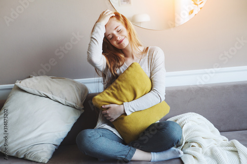Behang portrait of pretty young red haired smiling girl wearing pajamas getting up earl