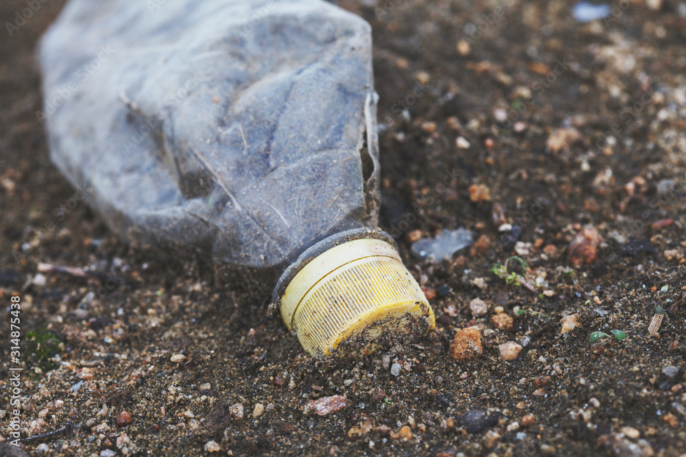 Obraz premium environmental pollution, ecological problem, plastic bottle on the ground, waste, earth, ocean pollution