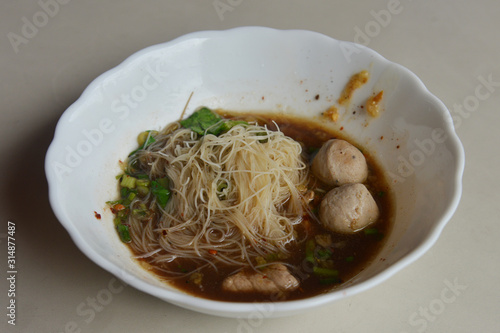 Thai Noodle With Stewed Soup (Kuay Tiew Ruer) served with Pork Ball and Pork. This is one of popular street food menu in Thailand.  photo