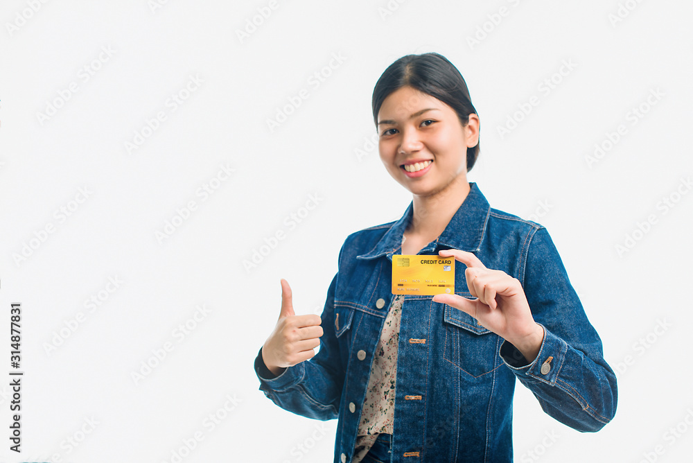 Portrait of a pretty young woman dressed in denim shirt holding credit card at her face isolated over white background. - Image
