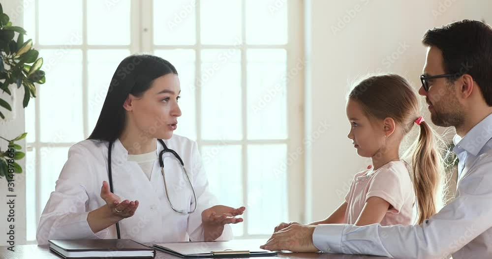 Professional female pediatrician talking with cute child girl and dad Professional female pediatrician talking with cute child girl and dad
