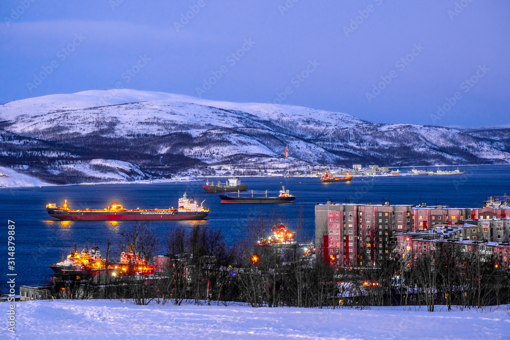 Murmansk, Russia - January, 5, 2020: Non-freezing seaport in the city of Murmansk in winter. The picture was taken at 2 p.m. in natural light at the height of a polar night - obrazy, fototapety, plakaty 