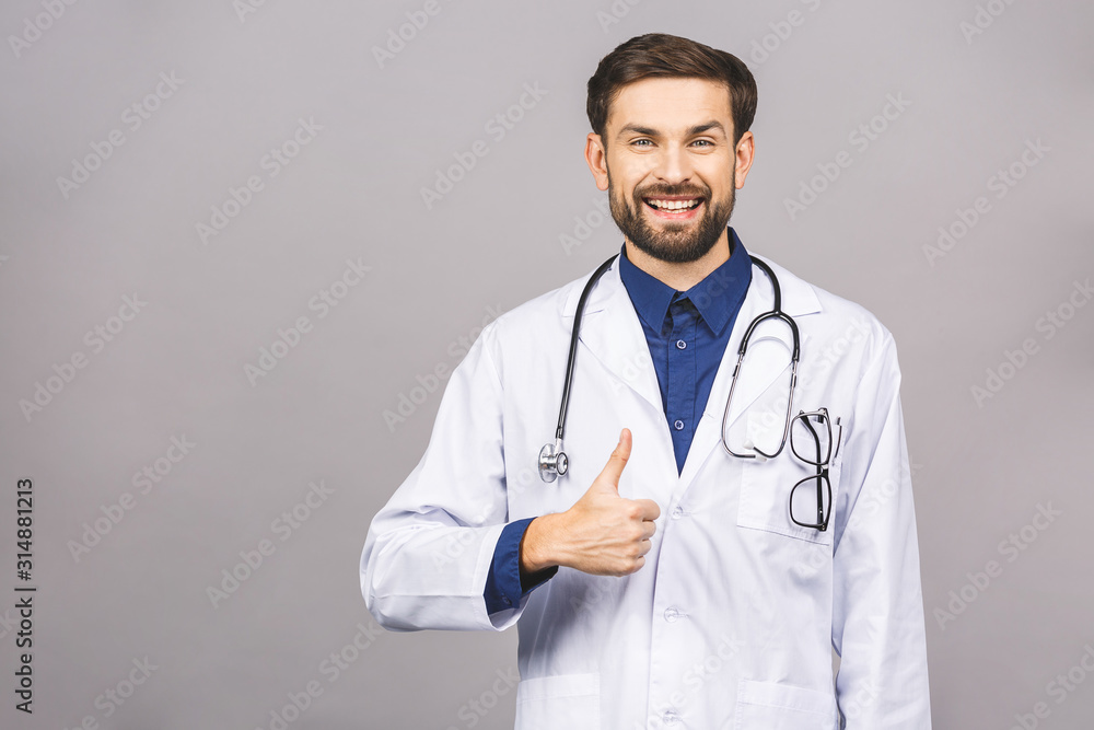 Portrait of cheerful smiling young doctor with stethoscope over neck in medical coat standing against isolated gray background. Thumbs up. Portrait of cheerful smiling young doctor with stethoscope over neck in medical coat standing against isolated gray background. Thumbs up.