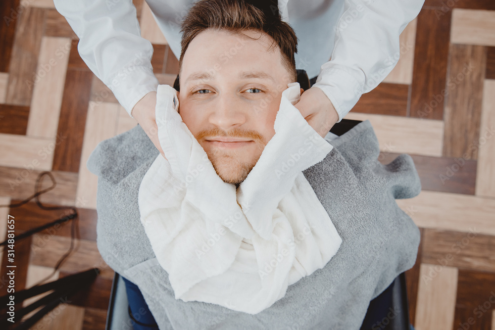 Barber steam face skin of man with hot towel before royal shave in