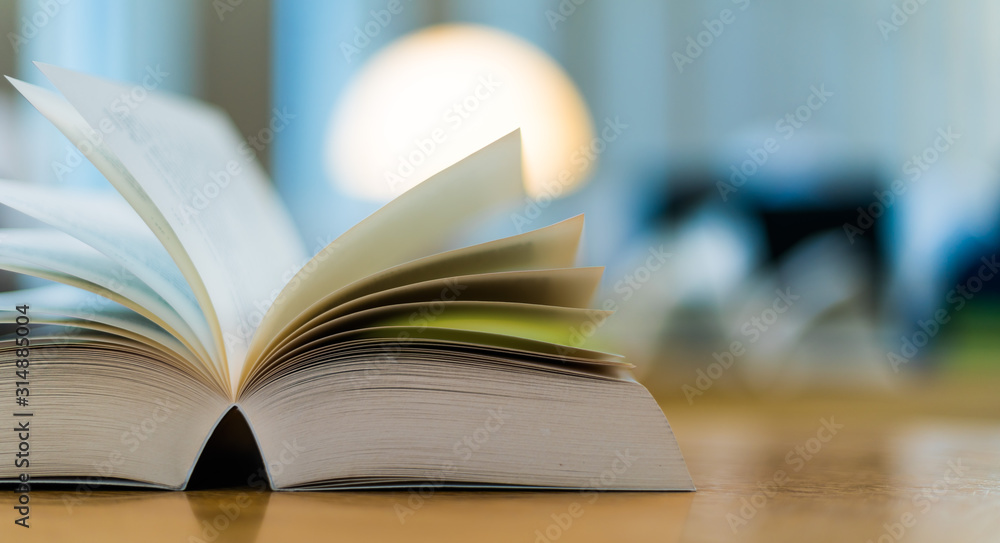 Fototapeta premium Otwórz książkę leżącą na stole w bibliotece