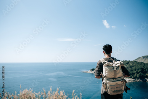 Man tourist with backpack on the mountain see the beautiful nature landscape of the sea