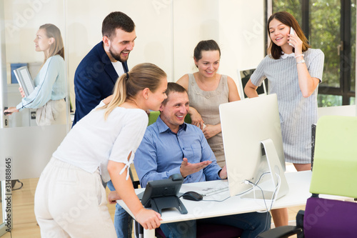Positive young business men and females brainstorming around computer monitor