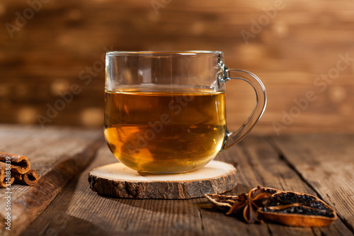  mug with tea on a wooden background with cinnamon, dry orange and star anise.