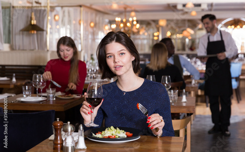 Portrait of young woman who is dining and drinking wine