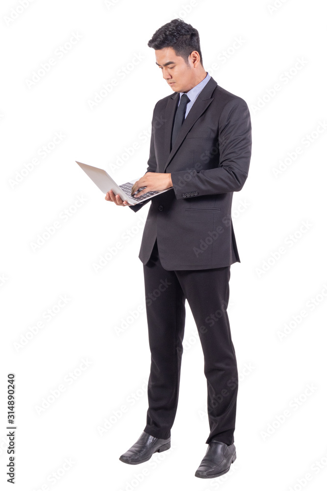 Young business man in suit standing with serious face looking and working on laptop isolated on white background, copy space and business concept. Young business man in suit standing with serious face looking and working on laptop isolated on white background, copy space and business concept.