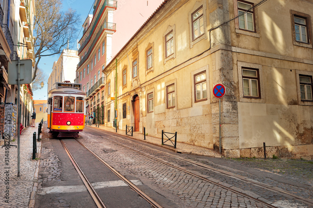 The traditional 28 tram passes in a street of the Alfama, Lisbon, Portugal