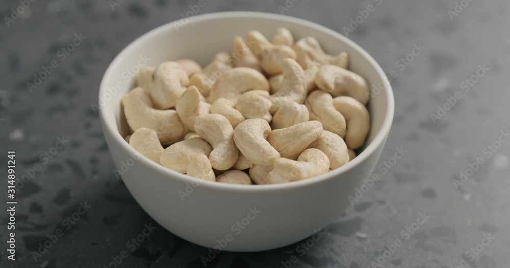 cashew nuts from white bowl on terrazzo countertop