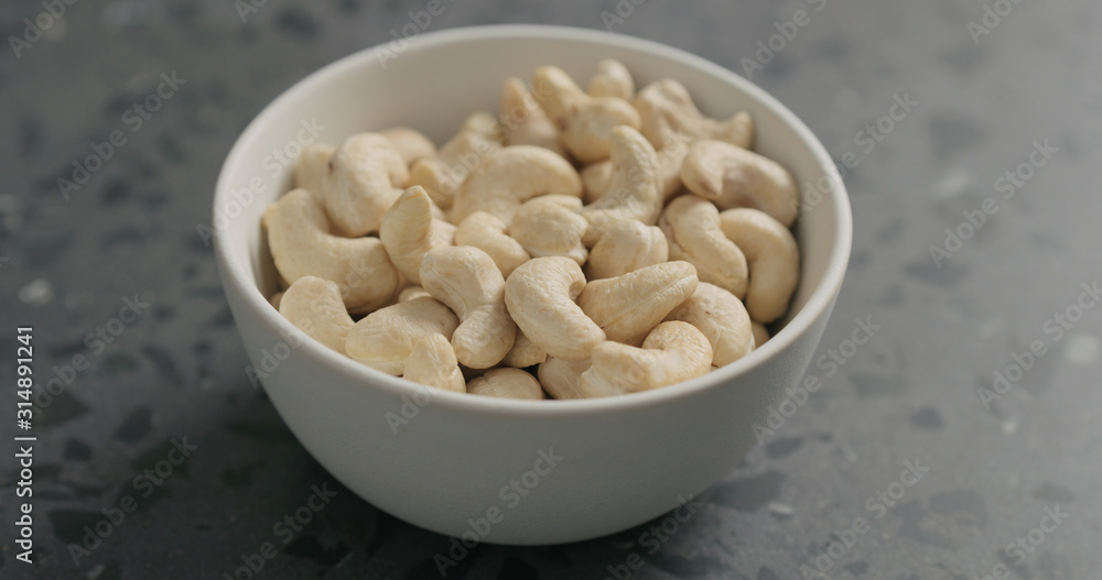 cashew nuts from white bowl on terrazzo countertop cashew nuts from white bowl on terrazzo countertop