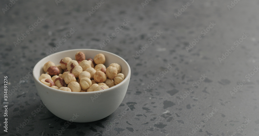 roasted hazelnuts in white bowl on terrazzo countertop roasted hazelnuts in white bowl on terrazzo countertop