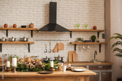 Christmas kitchen decor and copy space. Rustic cuisine at Christmas. Details of scandinavian cuisine in bronze color. Kitchen island table with festive table setting.