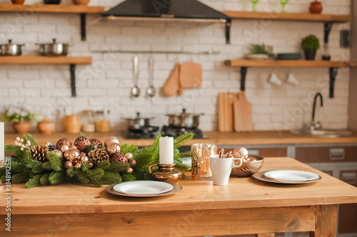 Christmas kitchen decor and copy space. Rustic cuisine at Christmas. Details of scandinavian cuisine in bronze color. Kitchen island table with festive table setting.
