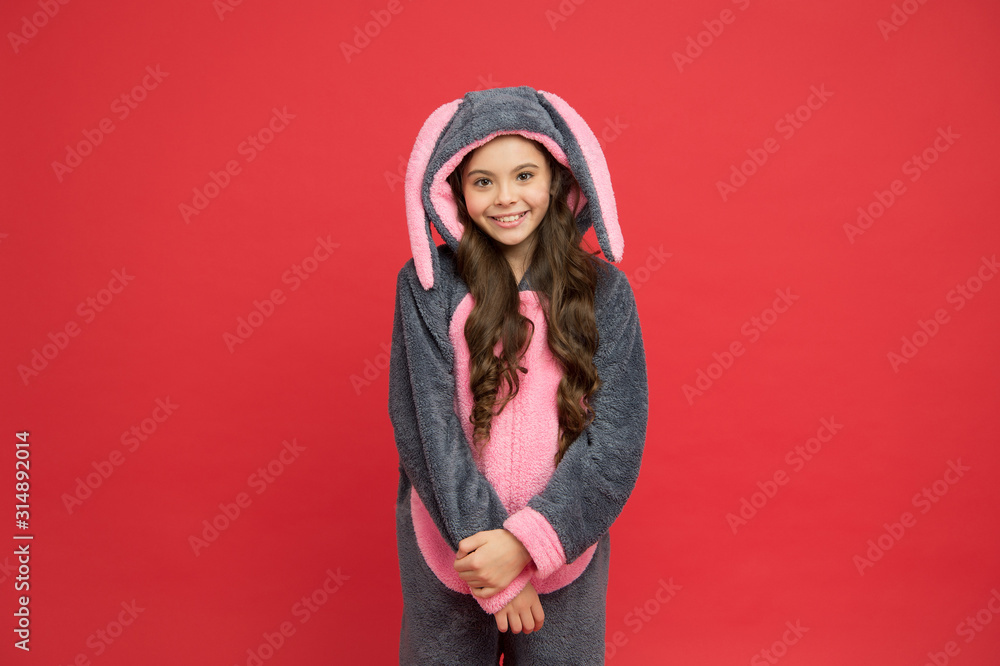 Happy girl in bunny pajamas. Lifestyle concept. Rest and relax. Cute bunny kid on red background. Baby animal character role. Adorable bunny. Gorgeous girl in bunny costume. Child in rabbit kigurumi Happy girl in bunny pajamas. Lifestyle concept. Rest and relax. Cute bunny kid on red background. Baby animal character role. Adorable bunny. Gorgeous girl in bunny costume. Child in rabbit kigurumi