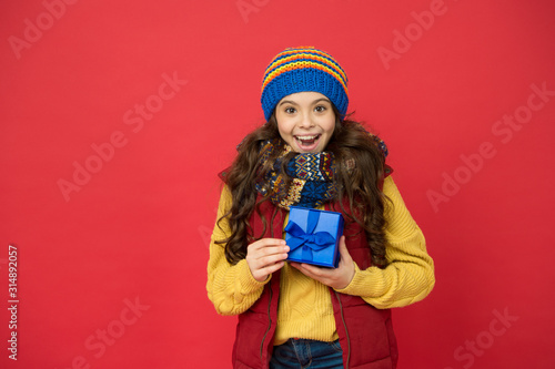 Feeling grateful. Holidays season. Happy childhood. Christmas gifts and souvenirs. Winter holidays. Happy kid in winter outfit red background. Pick some winter gifts for yourself. Wish list