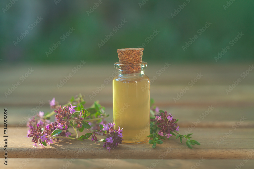 Naklejka thyme essential oil in beautiful bottle on table