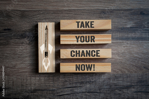 Wooden pieces on a wooden background with message Take your chance now