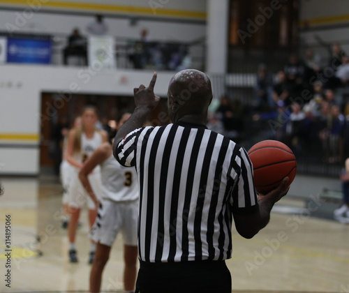 A basketball official signals one foul shot