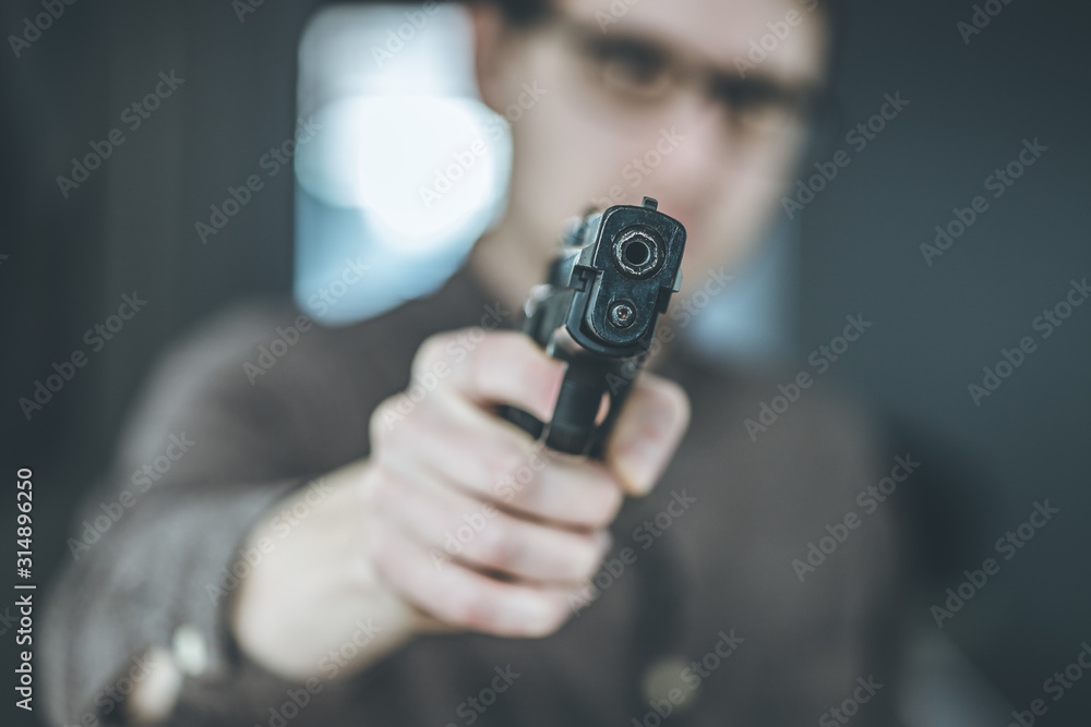 Crime or robbery concept: Man with black gun is aiming with his weapon Crime or robbery concept: Man with black gun is aiming with his weapon