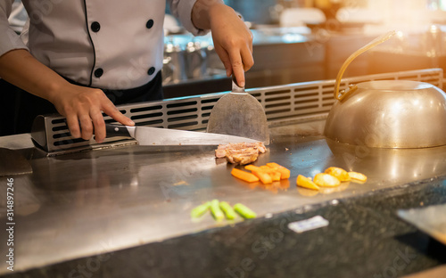 Slika na platnu Japanese chef cooking meat in teppanyaki restaurant