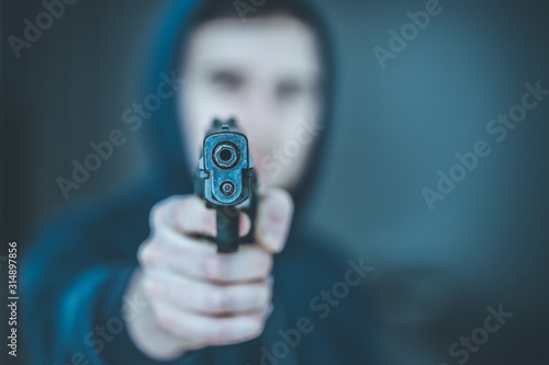 Crime or robbery concept: Man with black gun is aiming with his weapon photo