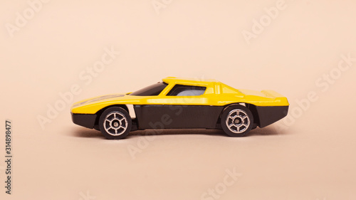 yellow little car. toy car on a beige background side view 